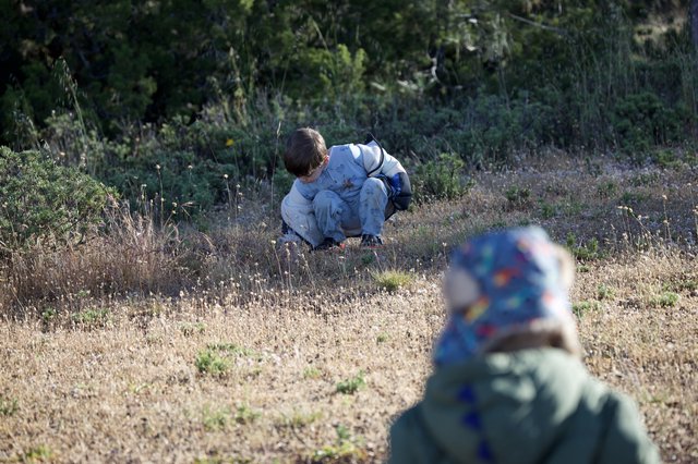 Young Explorer Crouching in Dry Grassland Field