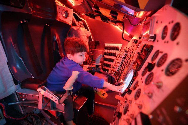 Young Visitor Explores Submarine Control Panel Exhibit