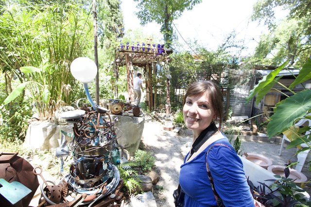 Woman Smiling Amid Eclectic Junk Art Garden