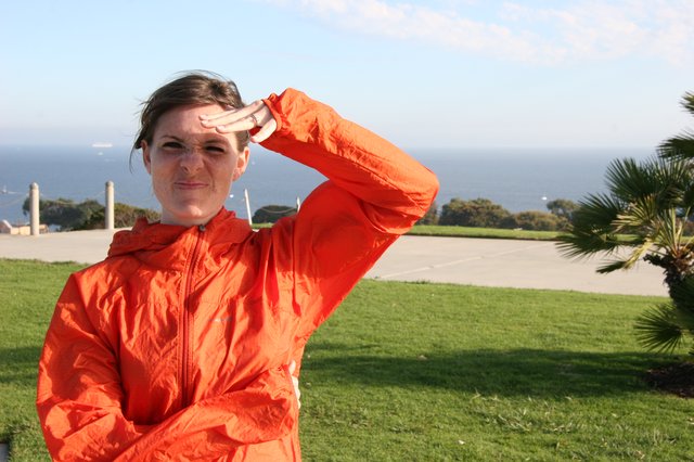 Woman in Orange Jacket Shielding Eyes Oceanside