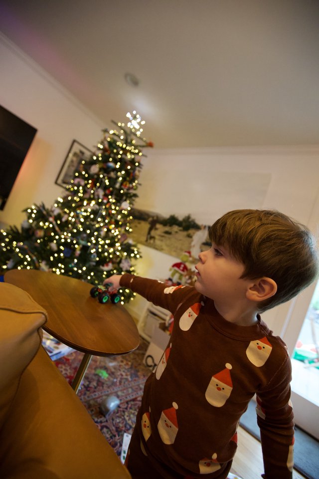 Child Pointing at Illuminated Christmas Tree in Wonder