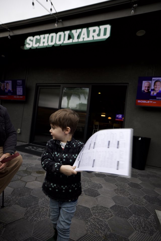 Young Boy Reading Sheet Music Outside Schoolyard Bar