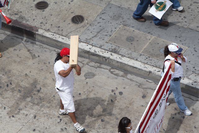 Man Carrying a Wooden Board on City Sidewalk