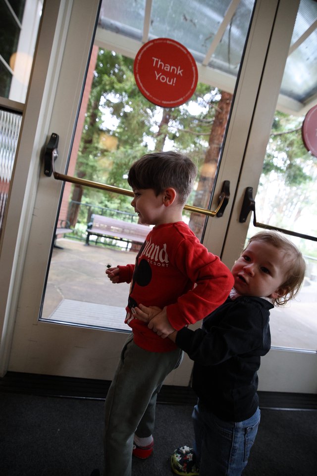 Two Young Children Playing Together at Glass Door Exit