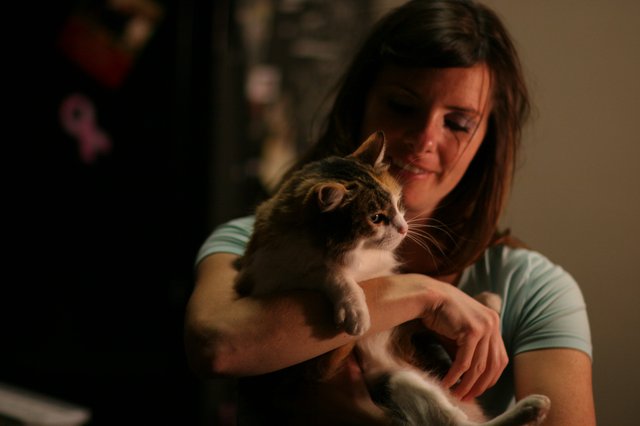 Woman Tenderly Holds Tabby Cat in Dim Light