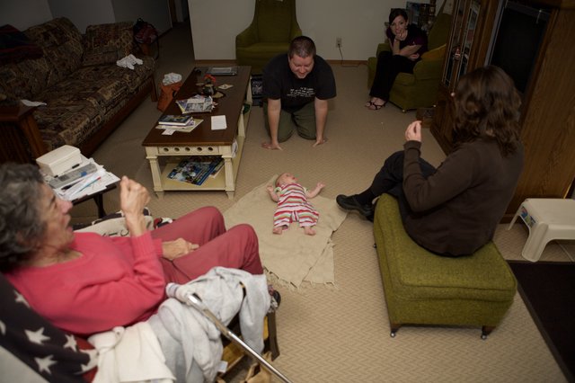 Family Gathering Around Newborn Baby on Floor