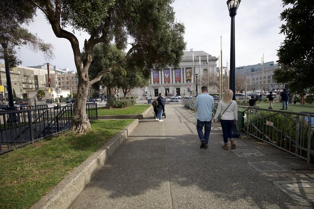 Couple Walking Through Urban Park Toward Museum
