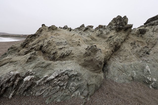 Jagged Coastal Rock Formation on Foggy Beach