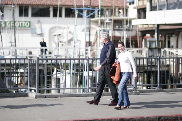 Couple Walking Along Waterfront Promenade in Bright Sunlight