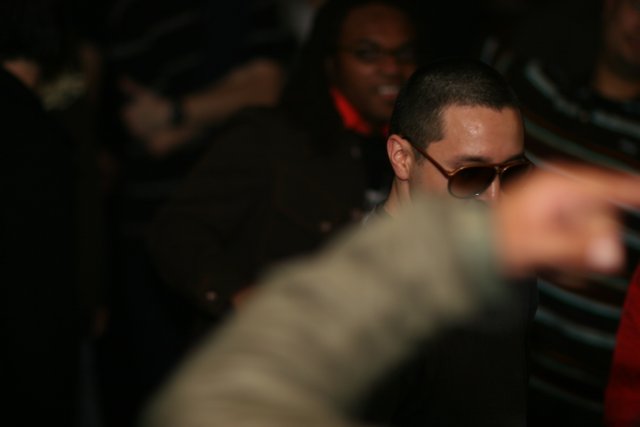 Man in Sunglasses Stands Out in Urban Nightlife Crowd