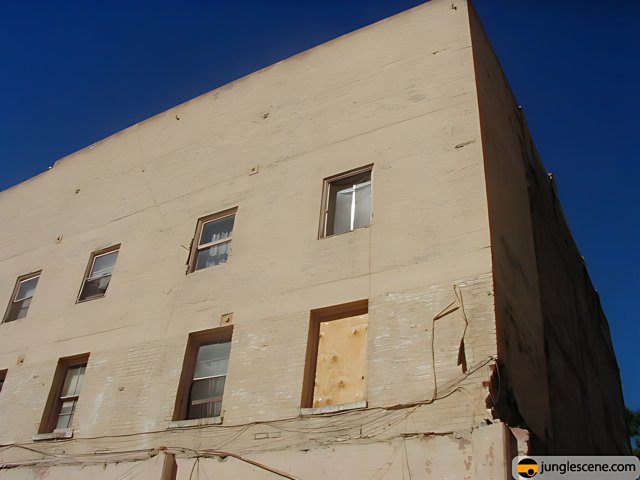 Abandoned Brick Building with Boarded Windows against Blue Sky