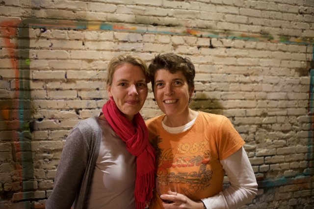 Two Women in Front of a Brick Wall