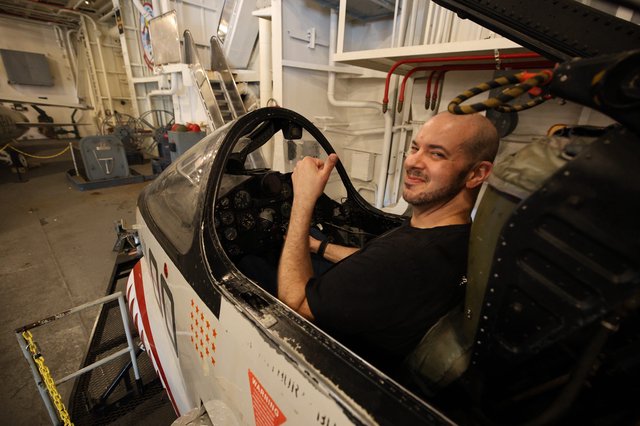 Man Sitting in Vintage Aircraft Cockpit Aboard USS Hornet