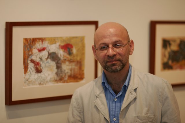 Bald Man Contemplates Two Paintings in Art Gallery