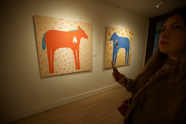 Woman Viewing Contemporary Horse Paintings in Art Gallery