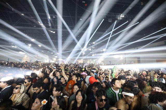 Massive Indoor Rave Crowd Bathed in Laser Beams