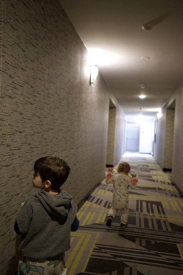 Two Children Running Down Modern Hotel Hallway
