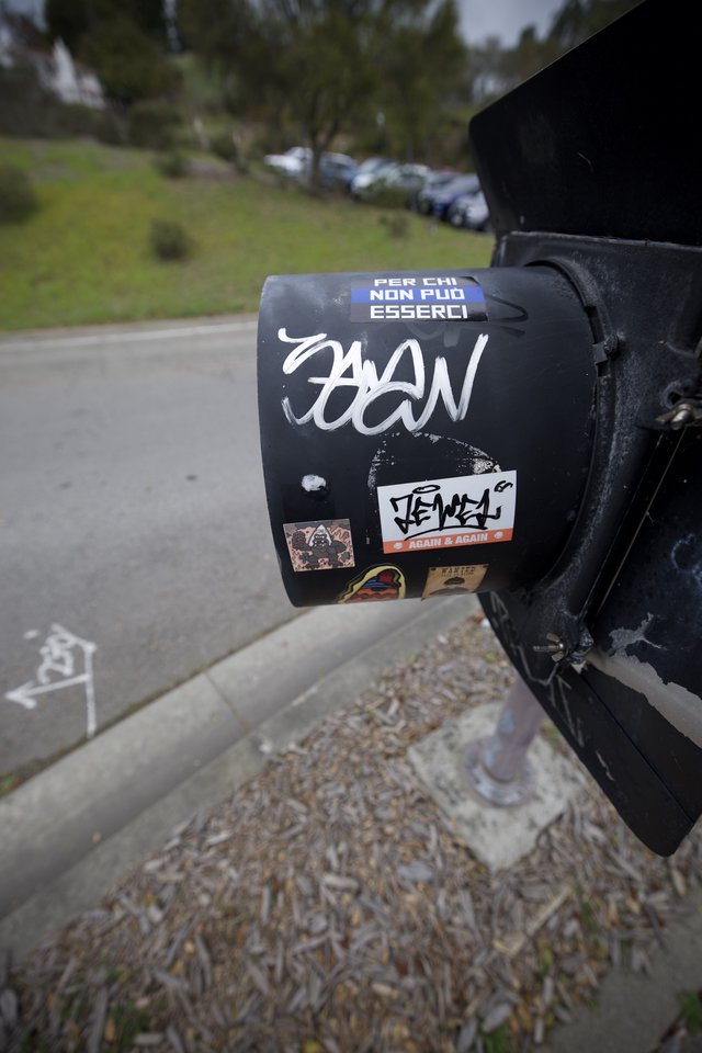 Sticker-Covered Black Mailbox in Suburban Setting