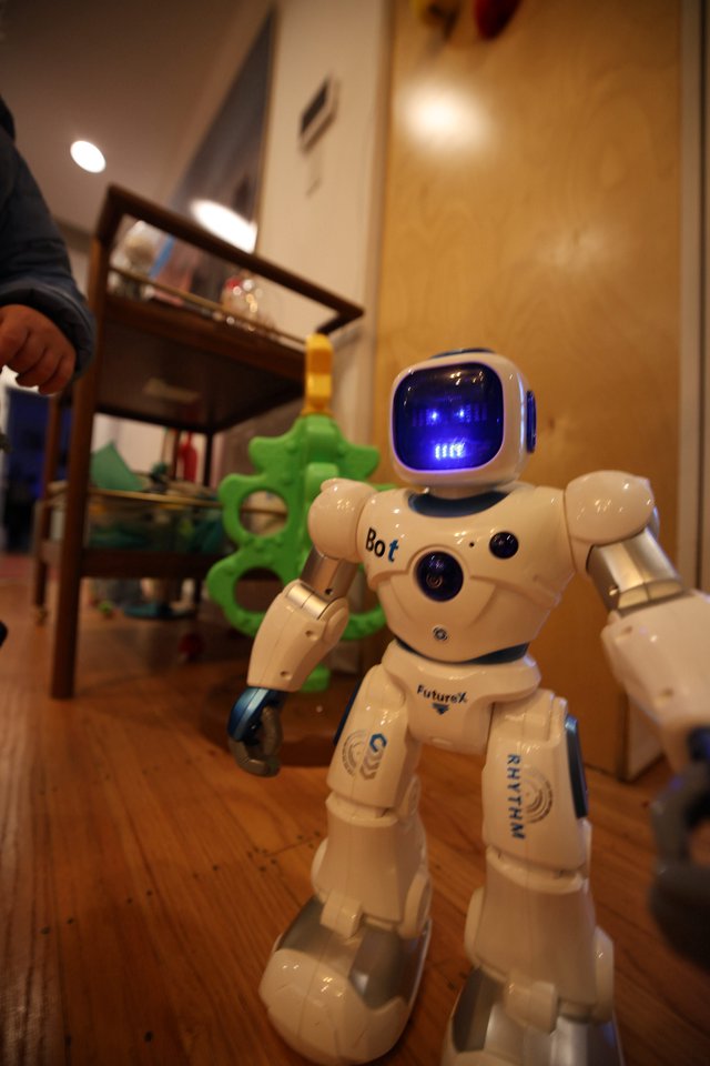White Robot Toy Standing on Wooden Floor at Home