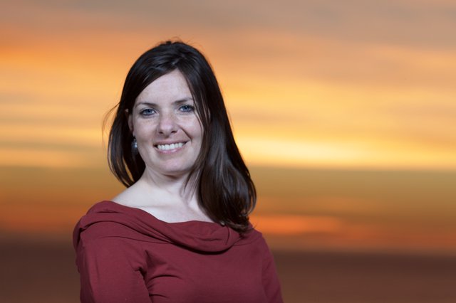 Woman Smiling Radiantly Against Golden Sunset Sky