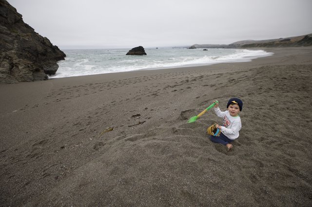 Young Child Playing in Sand at Rocky Coastline
