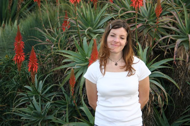 Young Woman Smiling Among Blooming Aloe Plants