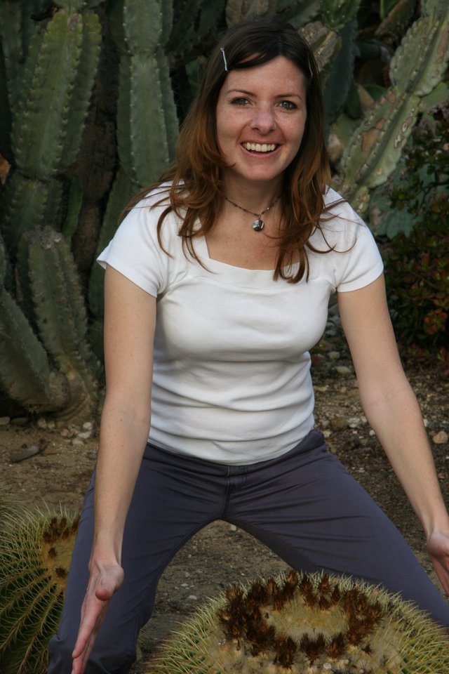 Smiling Woman Poses Among Desert Cacti Outdoors