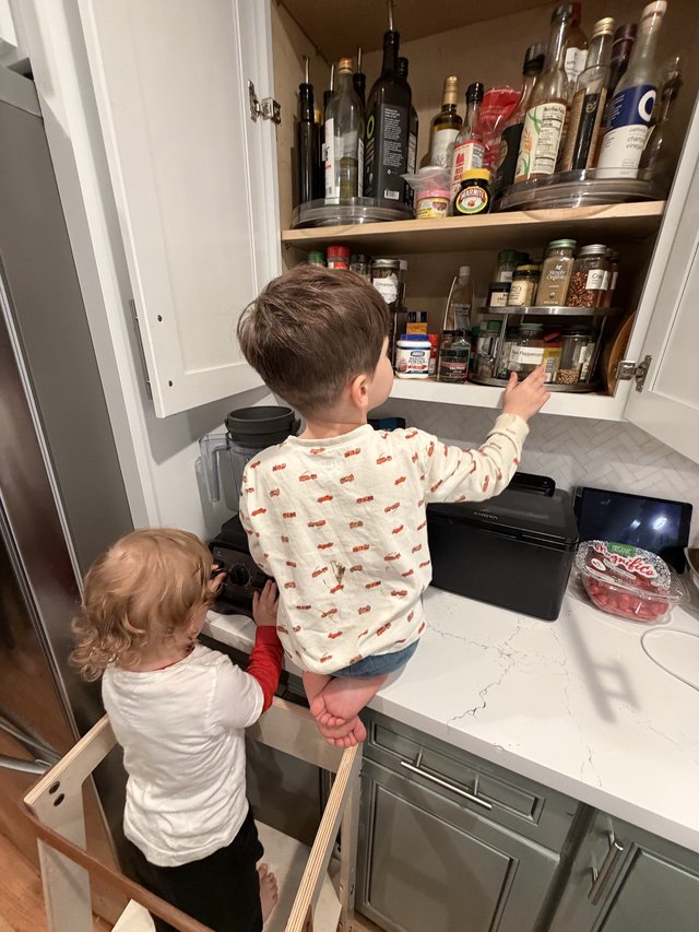 Young Brothers Exploring Kitchen Cabinet Together