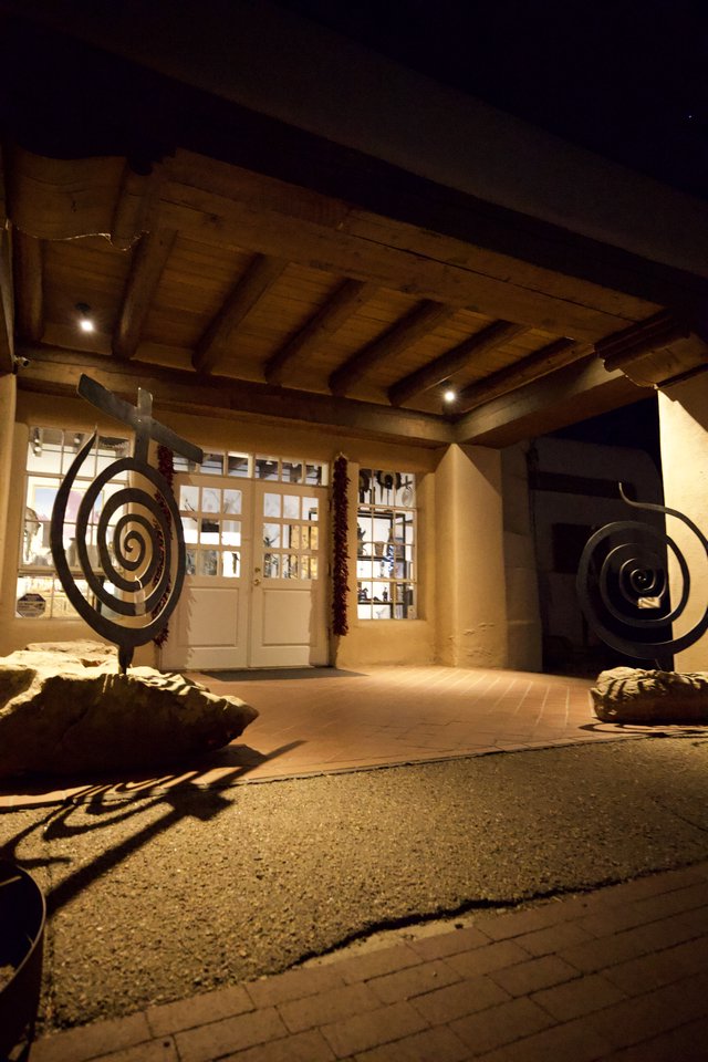 Spiral Sculptures Flanking Illuminated Adobe Entrance at Night