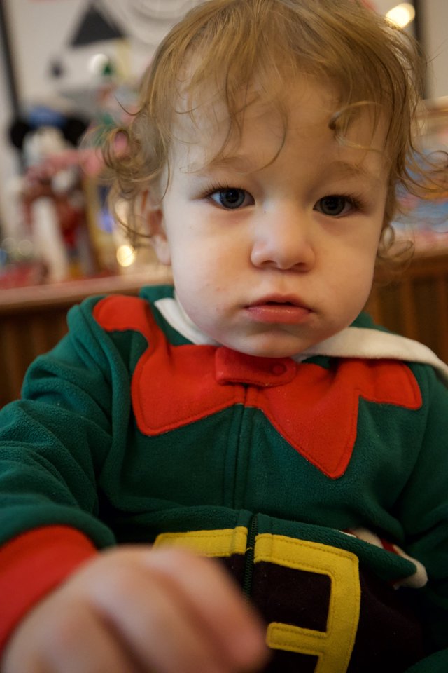 Toddler in Green Elf Costume with Serious Expression