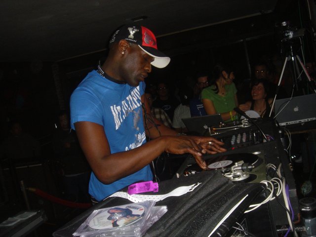Blue-shirted man working the turntables in a nightclub
