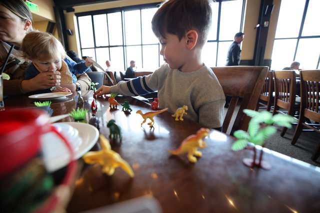 Children Playing with Dinosaur Toys at Restaurant Table