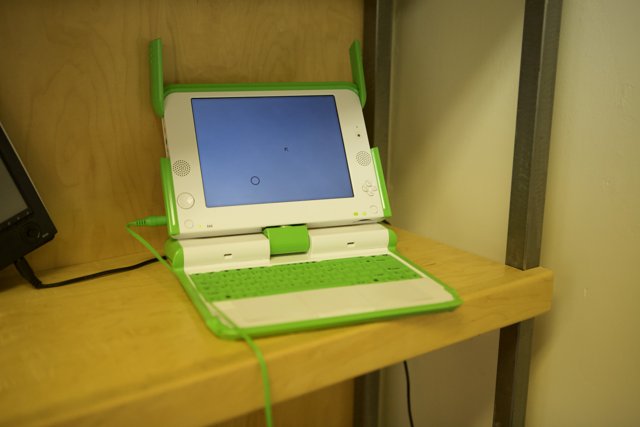 Green and White Laptop on Wooden Shelf