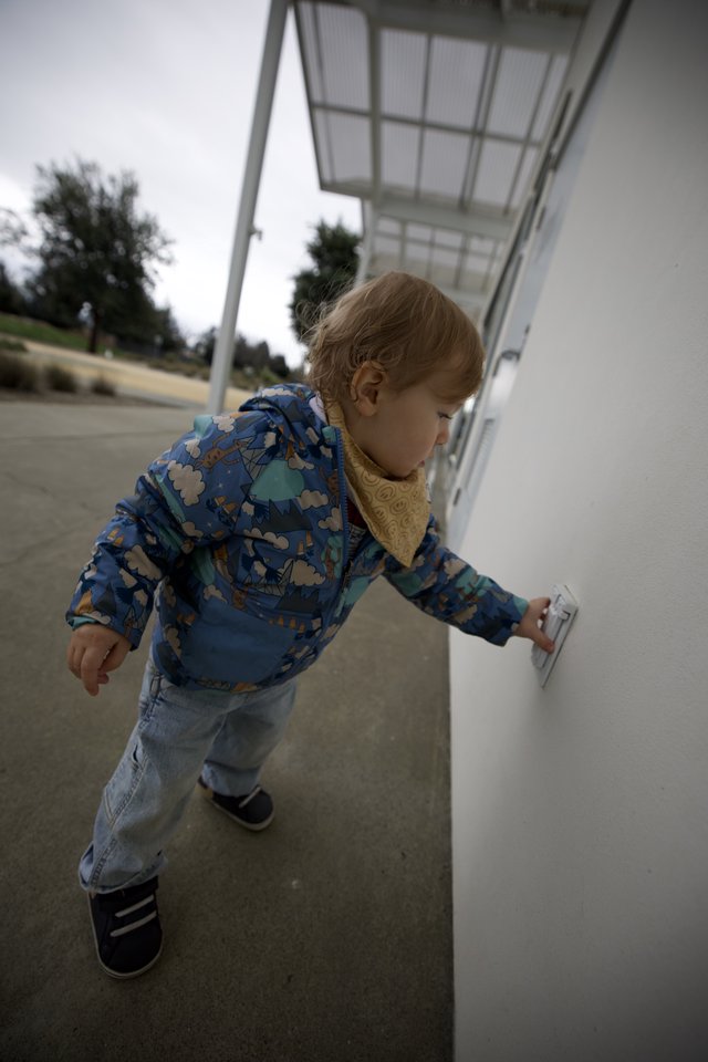 Young Child Exploring White Wall at Outdoor Location
