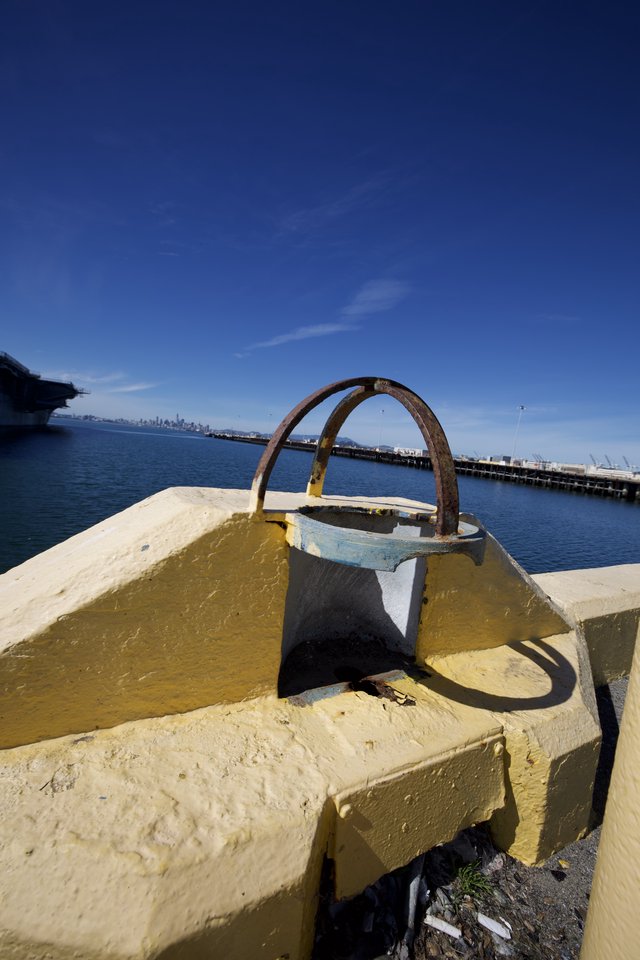 Rusted Mooring Bollard on Yellow Pier at Harbor