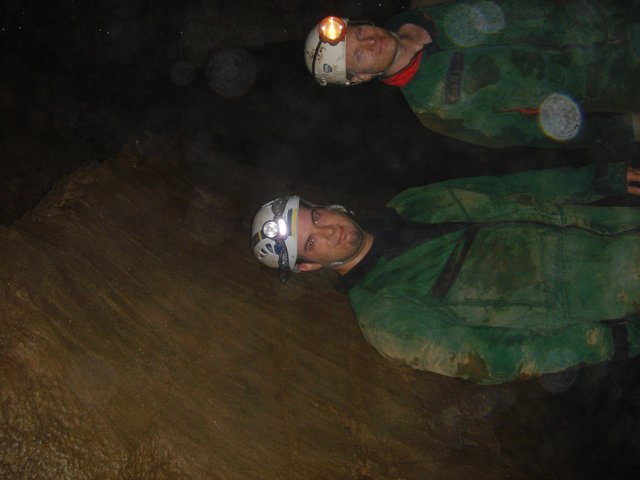 Two Men in Green Jackets Explore Natural Cave