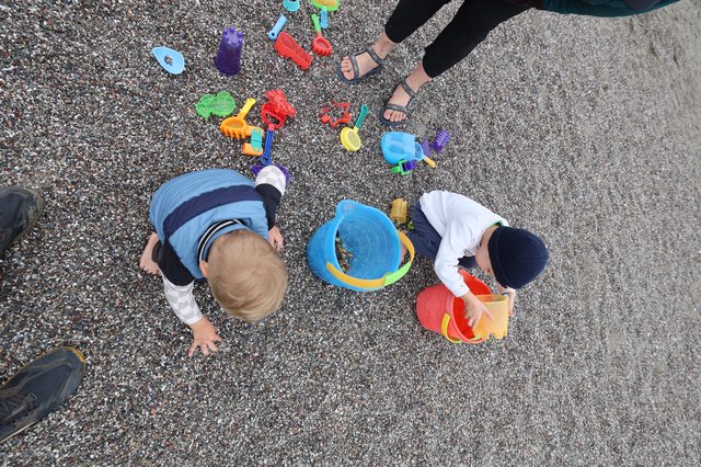 Children Playing with Beach Toys on Pebble Shore