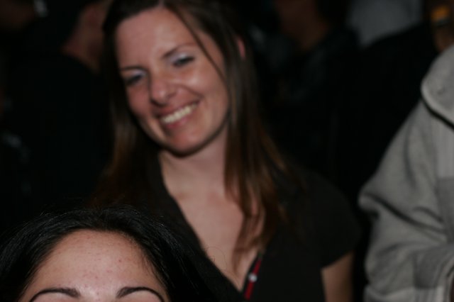 Woman Smiling Joyfully at Crowded Nighttime Event