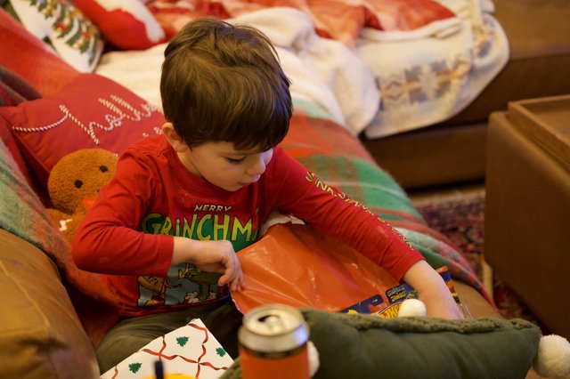 Young Boy Opening Christmas Presents in Red Grinch Pajamas