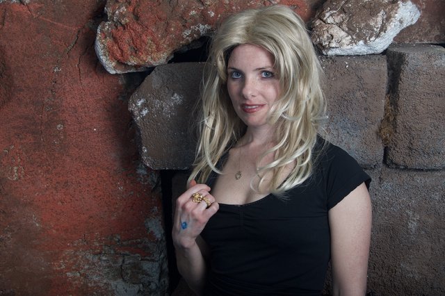Blonde Woman Leaning Against Rustic Stone Wall