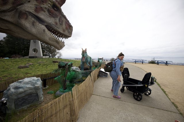 Woman with Stroller Encounters Dinosaur Display at Hilltop Park