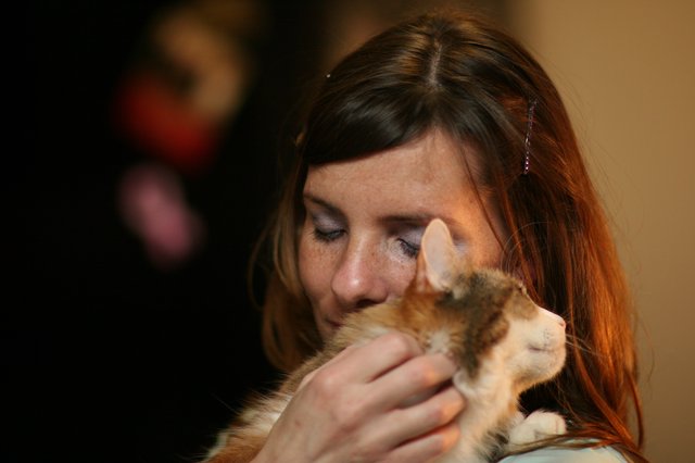 Woman Tenderly Nuzzling an Orange Tabby Kitten