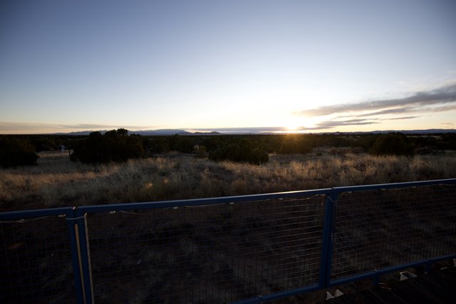 Sunset Over Desert Landscape with Metal Fence