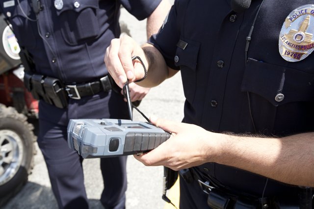 Police Officer Examining Car with High-Tech Device