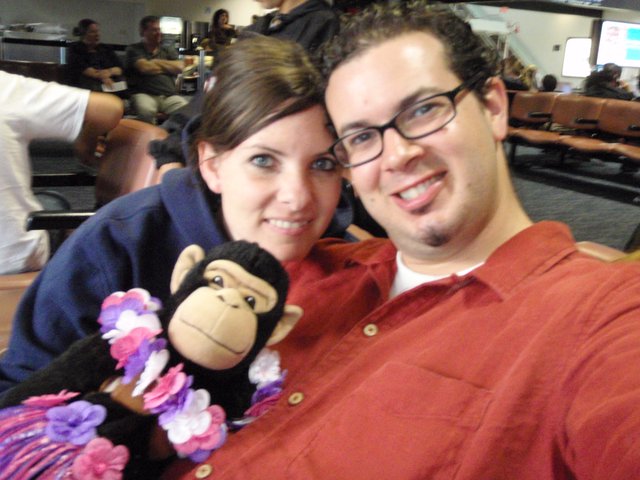 Couple Poses with Monkey Plush at Airport Gate
