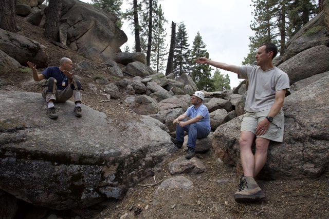 Three Men Resting on Rocks in the Wilderness
