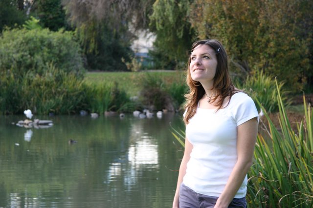 Young Woman Smiling by a Tranquil Park Pond