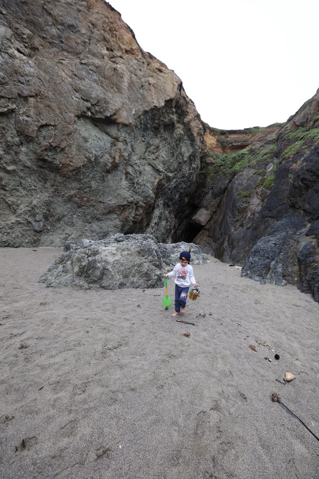 Young Explorer Discovers Sea Cave on Rocky Beach