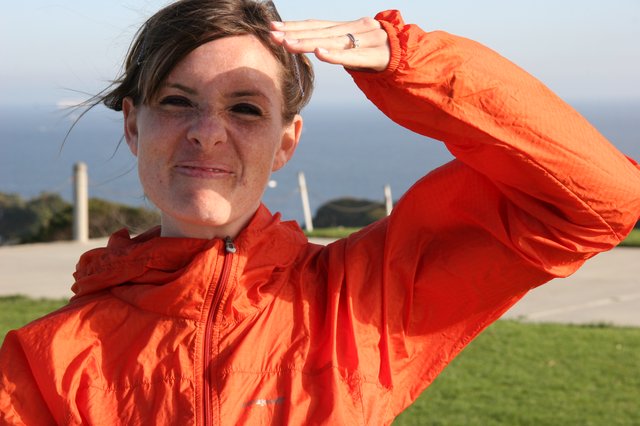 Woman in Orange Jacket Saluting by the Coast