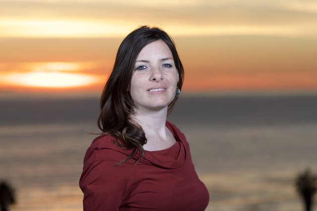 Woman Smiling Against a Golden Coastal Sunset